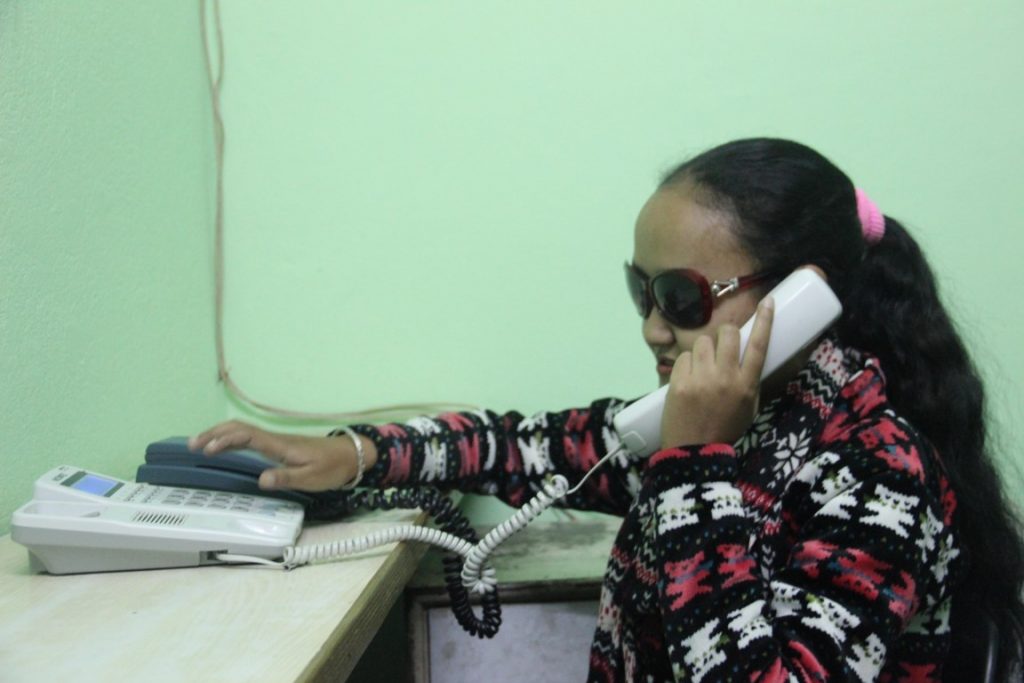 a visually impaired girl speaking on telephone in her office
