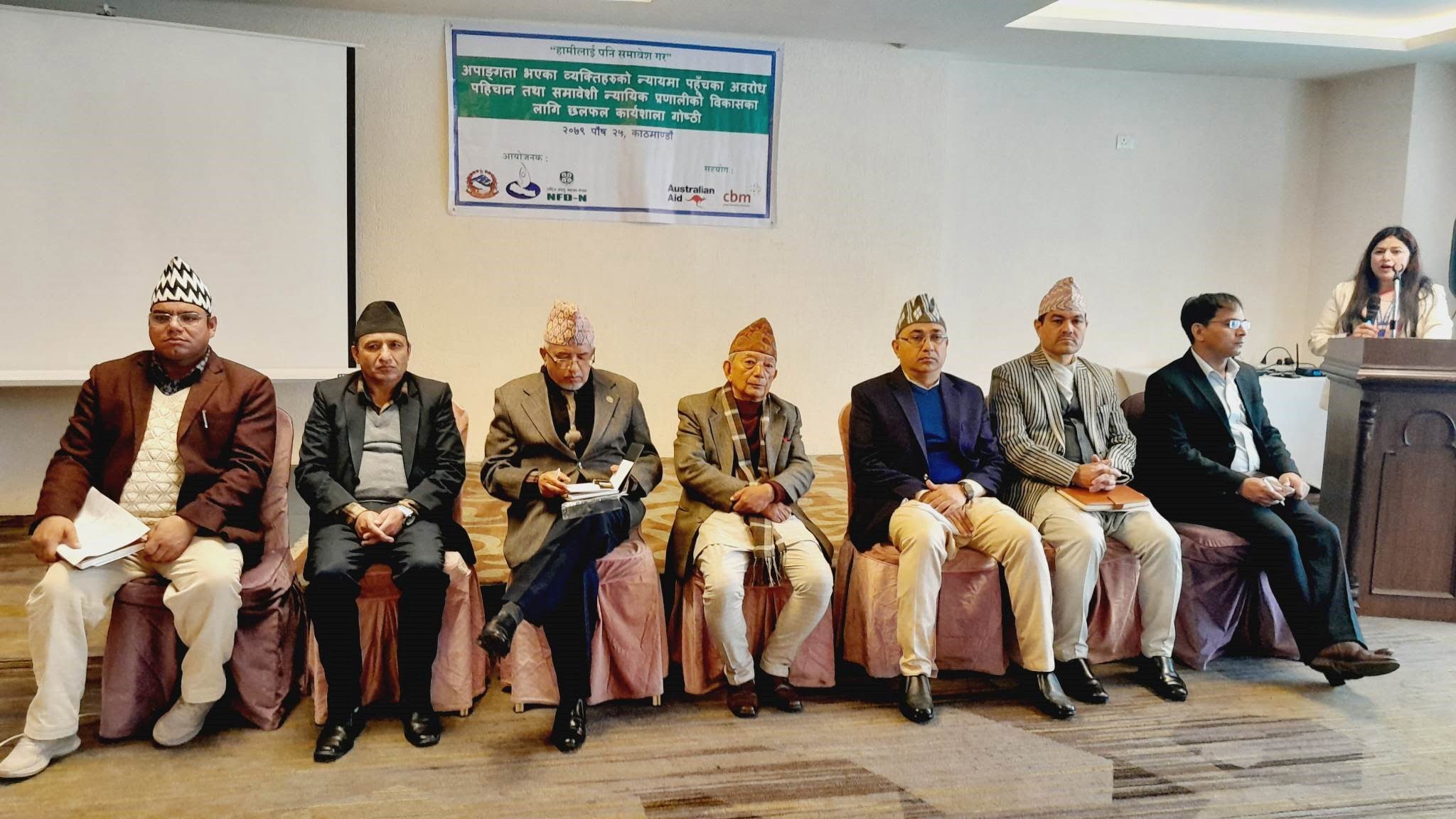 In this picture, 7 male and 1 femlae can be seen. In the chief guest of Top Bahadur Magar-president of NHRC, president of NFDN, DAO of Justice system Jay Narayan Acharya, Disability focal person of NHRC Ms. Kalpana Nepal can be seen in a picture. 6 of them are wearing hat and a banner of a program can be seen behind them.