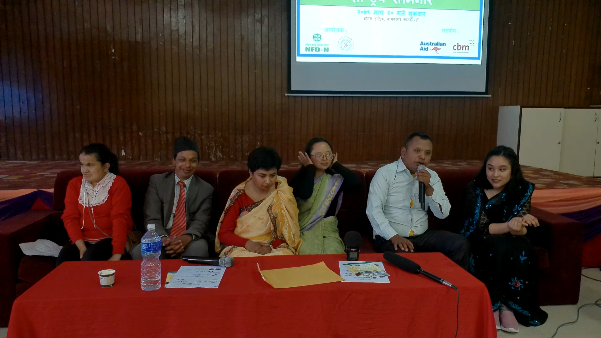 Self-advocates from the left Ms. Shanti phuyal, Nischal K.C, Ayushma Manandhar, Luja Shrestha, Shiva Shrestha, Prasansha Shakya are sitting in a chair in a hall. Shiva Shrestha can be seen as holding mike and responding to the questions.